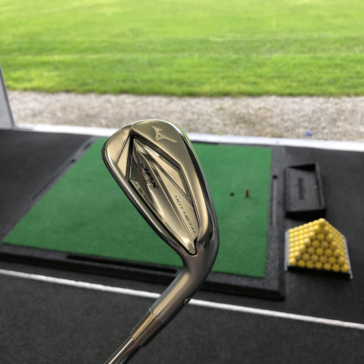 Mizuno wedge on the mat in the Express Golf fitting bay, looking out to the range